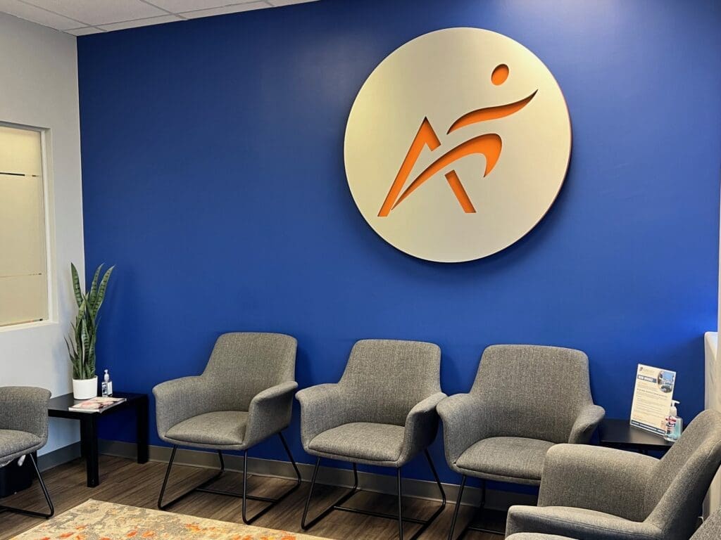 a photo of the interior lobby at Airrosti Allen. The Airrosti logo is displayed on the wall.